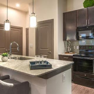 A stylish modern kitchen featuring an island countertop, dark cabinetry, and contemporary lighting.