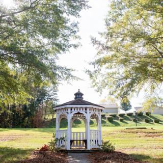 A charming gazebo surrounded by lush greenery and trees in a peaceful park setting.