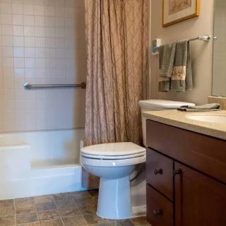 A tidy bathroom featuring a toilet, sink, and shower with a curtain.