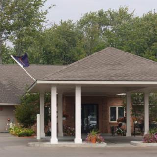 A building entrance with columns, surrounded by trees and greenery.