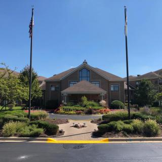 A well-landscaped building entrance with flags on a sunny day.
