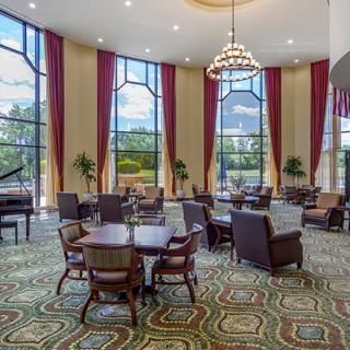 A luxurious lobby interior with elegant furniture, large windows, and a grand chandelier.