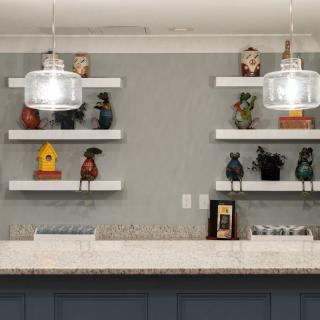 A modern kitchen featuring decorative shelves and stylish pendant lighting above a spacious countertop.