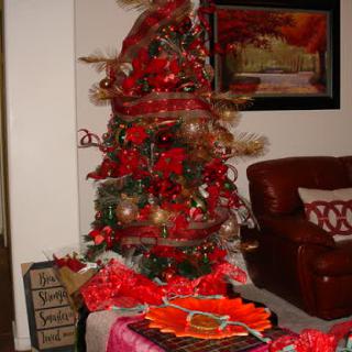 A beautifully decorated Christmas tree adorned with red accents, surrounded by holiday decorations.