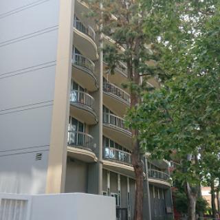 A modern apartment building with balconies surrounded by greenery.