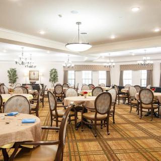 A well-lit dining area with multiple round tables and elegant chairs arranged neatly.