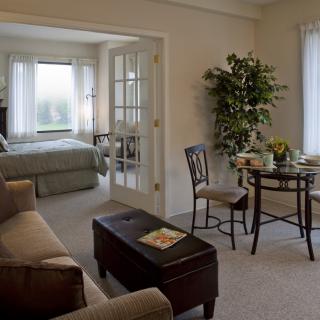 A cozy apartment interior featuring a living area and a bedroom with natural light.