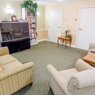 A cozy living room with comfortable chairs, a television, and a bookshelf.