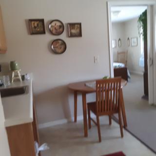 A cozy kitchen and dining area with a small table and chair, decorated with wall art.