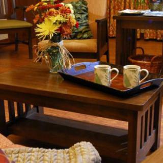A cozy living room with a wooden coffee table adorned with a floral arrangement and two mugs on a tray.