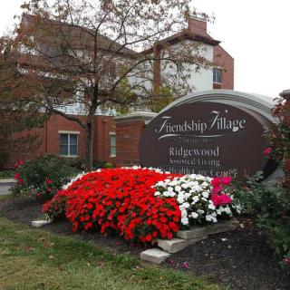 A landscaped entrance sign with vibrant red and white flowers in front of a building.