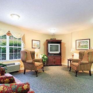 A cozy living room with armchairs and a TV cabinet.