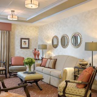 A beautifully decorated living room with a traditional design featuring a sofa, decorative mirrors, and elegant lighting.