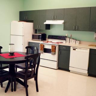 A modern kitchen with green cabinets, a dining table, and various appliances.