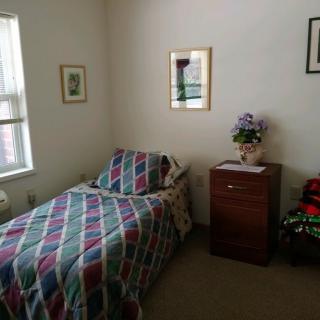 A small bedroom with a single bed, a nightstand, and decorative wall art.