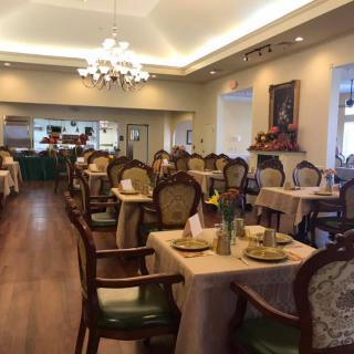 Elegant dining area with neatly arranged tables and chairs, featuring a chandelier.
