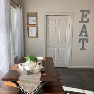 A bright dining area with a wooden table and decorative 'EAT' letters on the wall.