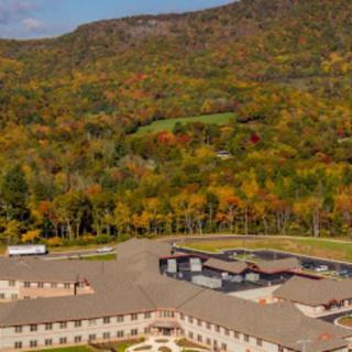 Aerial view of a building surrounded by vibrant autumn foliage and mountains.