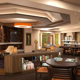 A modern library interior with comfortable seating, contemporary lighting, and shelves filled with books.