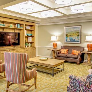 A cozy living room featuring a comfortable sofa, striped chairs, and a wooden bookshelf with decorative items.