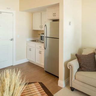 A cozy apartment corner featuring a small kitchen and living area with a refrigerator, couch, and modern decor.
