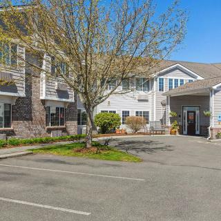 A sunny view of a residential building with a parking lot and trees.