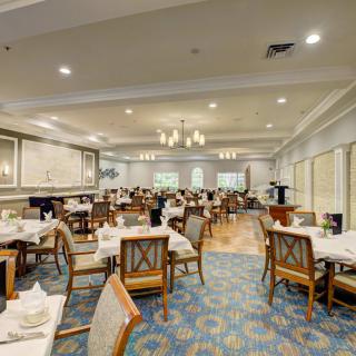 Elegant dining room with neatly arranged tables and chairs under a chandelier.