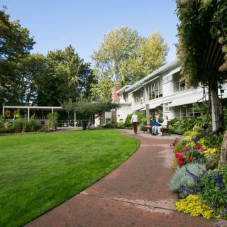 A charming house surrounded by a well-maintained garden with lush greenery and colorful flowers.