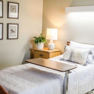 A cozy hospital room with a single bed, bedside table, and decorative elements.