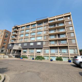 A modern residential building featuring multiple balconies and large windows.