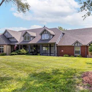 A spacious residential house with a well-maintained lawn and clear skies.