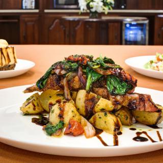 A delectable dish featuring grilled chicken served with roasted potatoes and spinach, drizzled with balsamic glaze.
