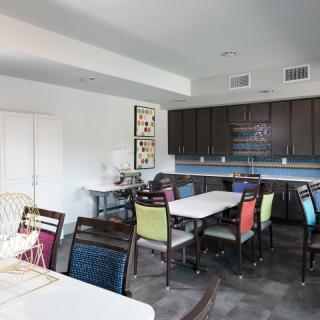 A modern kitchen and dining area featuring colorful chairs and sleek cabinetry.