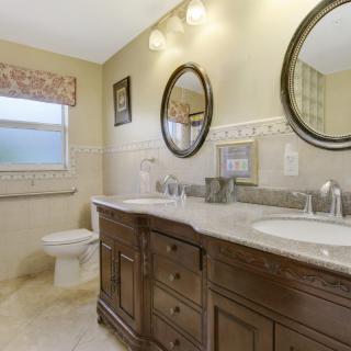 A stylish bathroom featuring a double vanity with wood cabinetry and two mirrors.