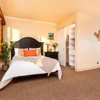 A cozy bedroom with warm lighting and stylish decor, featuring a comfortable bed, nightstand, and indoor plants.