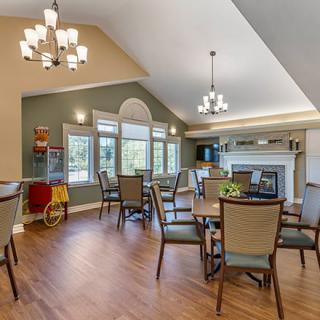 A spacious dining room with elegant chandeliers, wooden flooring, and a fireplace.