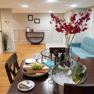 A modern living space featuring a dining setup with wine, flowers, and appetizers.