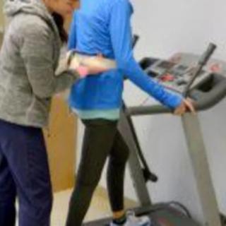 A person receiving assistance while walking on a treadmill for rehabilitation purposes.