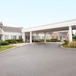 A building with a large driveway and landscaped surroundings.