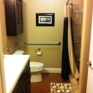 A small, neatly organized bathroom with a shower curtain and wall art.