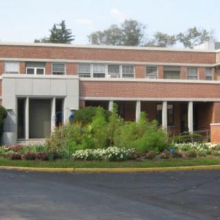 A brick building with a landscaped entrance and several windows.