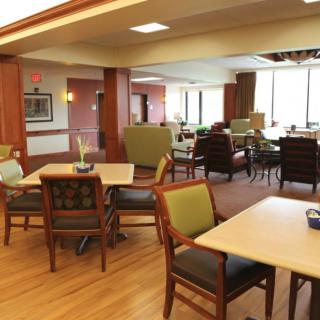 A spacious and well-lit communal living area with tables, chairs, and comfortable seating.