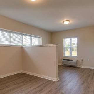 A modern, minimalist room with wood flooring and ample natural light from multiple windows.