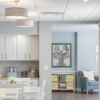 A modern interior featuring a kitchen with white cabinets and a cozy living area with comfortable seating and artwork.