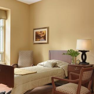 A cozy and well-lit bedroom featuring a single bed, two comfortable chairs, and decorative artwork on the wall.