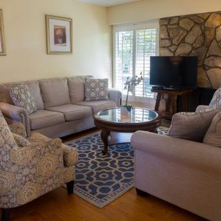 A cozy living room featuring a set of sofas, armchairs, a coffee table, and a television against a stone accent wall.