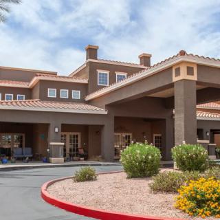 A hotel building with an entrance surrounded by landscaped gardens under a cloudy sky.