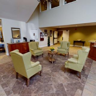 A modern, spacious lobby with a central seating area featuring four chairs arranged around a small table.