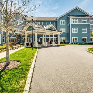 A modern residential building with a driveway and well-maintained landscaping on a sunny day.