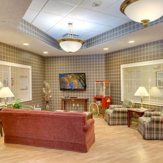 A cozy living room with plaid wallpaper, featuring comfortable seating, a television, and a popcorn machine.